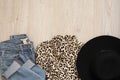 Women fashion clothes on wooden background. Flat lay female styled look. Shirt, felt hat and jeans. Top view. Shopping Concept.