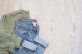 Women fashion clothes on wooden background. Flat lay female styled look. Sweater and jeans. Top view. Shopping Concept. Fashion