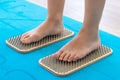 Women feet are standing on a board with sharp nails, Sadhu Board. yoga practice. pain, trial, health. blue yoga mat. Royalty Free Stock Photo