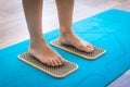 Women feet are standing on a board with sharp nails, Sadhu Board. yoga practice. pain, trial, health. blue yoga mat. Royalty Free Stock Photo