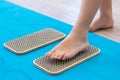 Women feet are standing on a board with sharp nails, Sadhu Board. yoga practice. pain, trial, health. blue yoga mat. Royalty Free Stock Photo