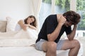 Women focus, depressed man sitting on the edge of the bed in bedroom. Young couple having problems with sex life. Royalty Free Stock Photo