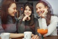 Women girlfriends in a cafe are having a fun chatting and drinking their beverages. View from behind glass.