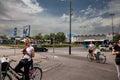 Women, girls, riding bicycle by the Novi Sad train station, Vojvodina, waiting to cross a street with cars at a red traffic light.