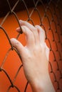 Women hand catching iron bar on orange background, imprison feel