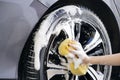 Women hand with foam sponge washing car wheel Royalty Free Stock Photo