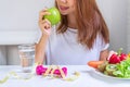 Women hand holding green apple with fruits, vegetables, water, dumbbell and tape measure on white table background. Selection of Royalty Free Stock Photo