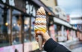 A women hand holding mixed colorful tasty ice cream soft cream cone with blurred shop background