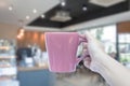 Women hand holding mug with blurred cafe Royalty Free Stock Photo