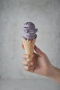 Women hand holding purple ice cream cone on concreat background Royalty Free Stock Photo