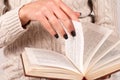 Young Girl\'s Hand with Stylish Black Nails Holds Book, Woman in Wool Sweater Immersed in Reading Royalty Free Stock Photo