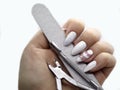 Manicure tools - pusher, cuticle nipper and buffer in hand with long white nails Royalty Free Stock Photo