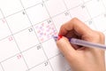 Women hand with pencil drawing hearts shape in calendar for Valentines day Royalty Free Stock Photo