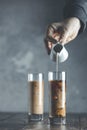 Women hand is pouring homemade sour cream from small jar to glass with brew cold coffee and ice. Cold summer drink on a dark Royalty Free Stock Photo