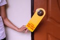 Woman hands putting closed door with please do not disturb sign on handle at hotel room Royalty Free Stock Photo