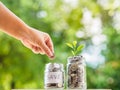 Women hand putting money coin into glass jar for saving money. s Royalty Free Stock Photo