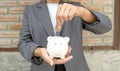 Women hand in suit putting coins into white piggy bank, step up start-up business to success, Saving money for future plan and Royalty Free Stock Photo