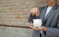 Women hand in suit putting coins into white piggy bank, step up start-up business to success Royalty Free Stock Photo