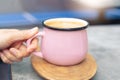 Women hand touch pink cup of hot coffee on wooden plate Royalty Free Stock Photo