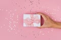 Women hands holding a gift or gift box decorated with confetti on a pink pastel table top view Royalty Free Stock Photo