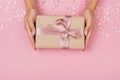 Women hands holding a gift or gift box decorated with confetti on a pink pastel table top view Royalty Free Stock Photo