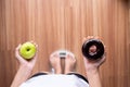 Woman hands holding green apple and baked chocolate donut during standing on weighing scale,Healthy diet,Dieting concept Royalty Free Stock Photo