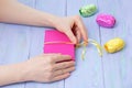 Women hands wrapped in a pink gift box with a yellow ribbon violet wooden background. Cose-up