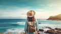 A women with hat and backpack overlooking sea with mountains by the side