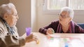 Women having fun playing Parcheesi board game in a geriatric