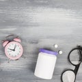 health care style. copy space.plastic bottle with pills, clock and glasses on blue wooden background. Royalty Free Stock Photo