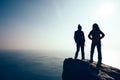 Women hikers looking at the view on seaside mountain top rock edge Royalty Free Stock Photo