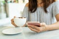 Women hold a cup of coffee while using mobile phone