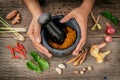 The Women hold pestle with mortar and spice red curry paste ingredient of thai popular food on rustic wooden background. Spices i Royalty Free Stock Photo