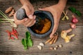 The Women hold pestle with mortar and spice red curry paste ingredient of thai popular food on rustic wooden background. Spices i Royalty Free Stock Photo