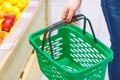 Women holding empty green shopping basket near fruits window in the supermarket. Shopping concept