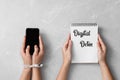 Women holding smartphone and notebook with words DIGITAL DETOX on light grey marble background, top view Royalty Free Stock Photo