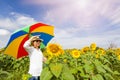 A women holding umbrella with field blooming of sunflowers.