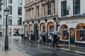 Women holding umbrellas walk past Harvie And Hudson shop in St James, London, UK