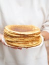 Women holding white plate with pile thin pancakes