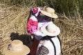 women with indigenous straw hat from the uros culture,standing on floating island of totora on lake titicaca dressed with baby in