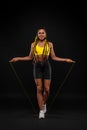 Women with jumping rope on black background. Beautiful young women standing with a jumping rope Royalty Free Stock Photo