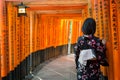 Women in kimono stand at Red Torii gates in Fushimi Inari shrine, Kyoto, Japan