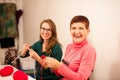 Women knitting with red wool. Eldery woman transfering her knowledge of knitting on a younger woman on handcraft workshop. Royalty Free Stock Photo