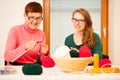 Women knitting with red wool. Eldery woman transfering her knowledge of knitting on a younger woman on handcraft workshop. Royalty Free Stock Photo