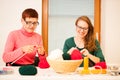 Women knitting with red wool. Eldery woman transfering her knowledge of knitting on a younger woman on handcraft workshop. Royalty Free Stock Photo