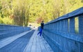 Women leaning on the railing of the old bridge, admiring the surrounding greenery in daylight. Royalty Free Stock Photo