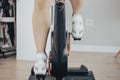 Women leg with white cycling boots cycling on a spinning gym bike indoor scene with motion fast blur Royalty Free Stock Photo