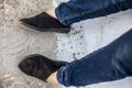 Women legs or female legs shod in black colored shoes and blue colored jeans.