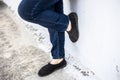 Women legs or female legs shod in black colored shoes and blue colored jeans.