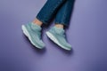 Women legs in jeans and running shoes on purple Royalty Free Stock Photo